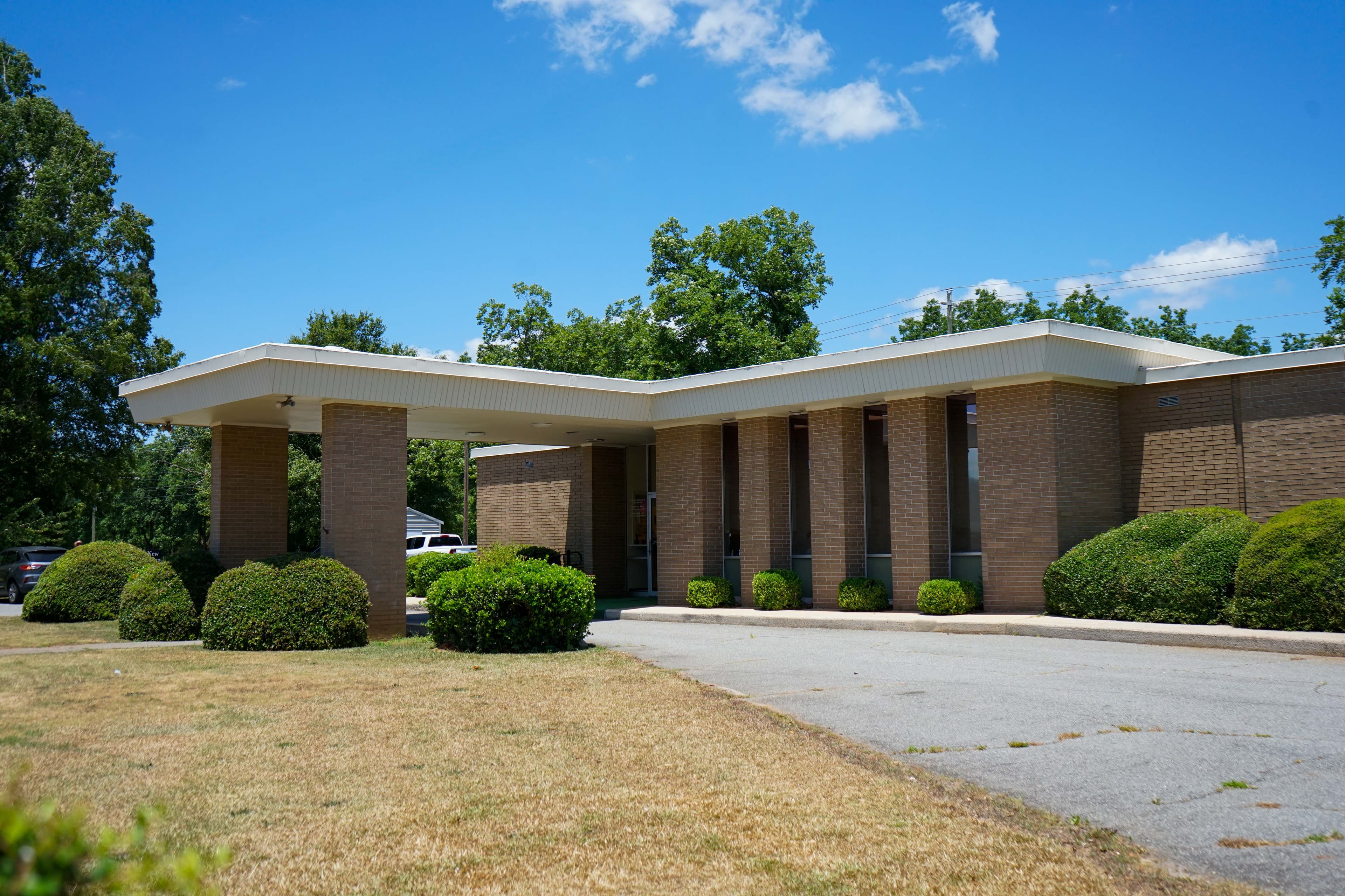 Houston Primary Care at Fort Valley is surrounded by trees and bushes on a sunny day .